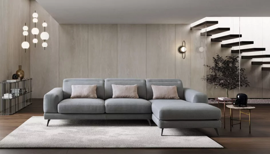 Salon italien LeCOMFORT — canapé d'angle gris en tissu, coussins poudrés et escalier suspendu, ambiance L'atelier Contemporain à Biarritz